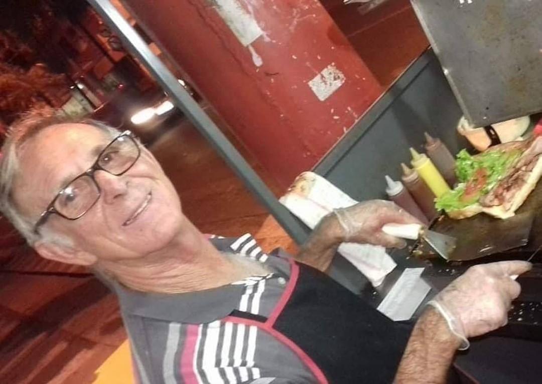 Seu Carlão preparando um Hot Dog na chapa, à noite, em Birigui